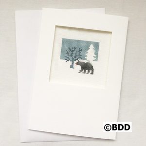 A bear is standing in the snow next to a tree.