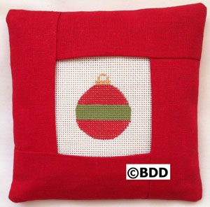 A red pillow with a green and white ornament on it.