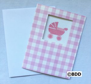 A pink baby carriage card sitting next to an open envelope.