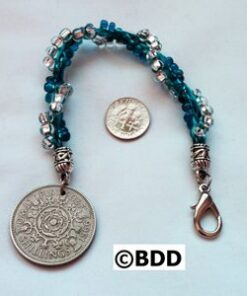 A coin is shown with a beaded bracelet.