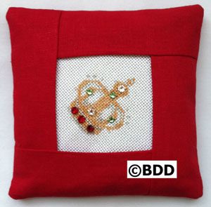 A red pillow with a picture of a gold and diamond ring.