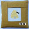 A pillow with a bee on it and the picture of a beehive.