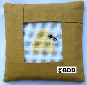 A pillow with a bee on it and the picture of a beehive.