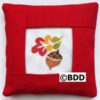 A red pillow with an autumn leaf picture on it.