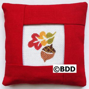 A red pillow with an autumn leaf picture on it.