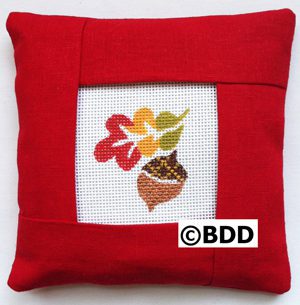 A red pillow with an autumn leaf picture on it.