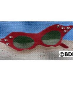 A red pair of sunglasses sitting on top of sand.