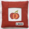 A red pillow with an orange pumpkin on it.