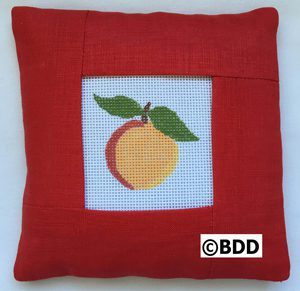 A red pillow with an orange on it.