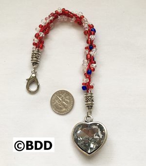 A red and white beaded bracelet with a silver heart charm.