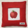 A red pillow with an apple on it.