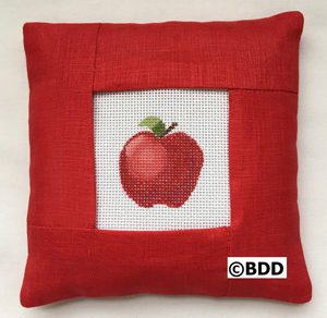 A red pillow with an apple on it.