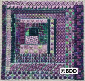 A purple and green quilt with a square design.