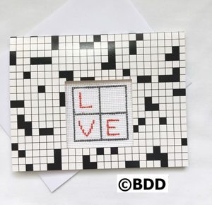 A picture frame with the word love written in cross stitch.