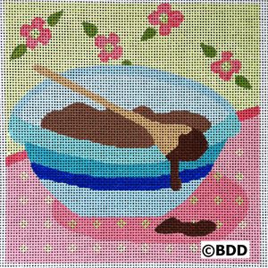 A bowl of chocolate covered dough on a pink and blue table.