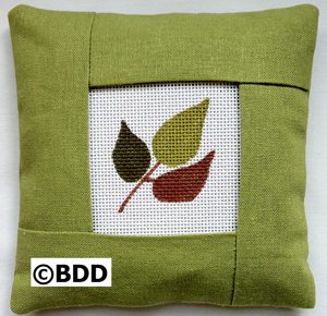 A green pillow with leaves on it.