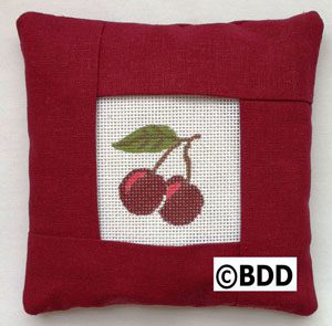 A red pillow with cherries on it.