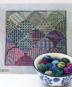 A bowl of yarn and a cross stitch pattern.