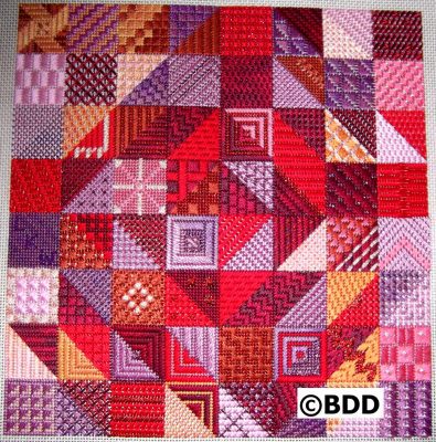 A red and purple quilt with many different designs.