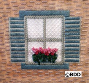 A window with shutters and flowers in the window.