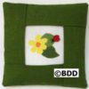 A green pillow with a picture of a flower and a ladybug.