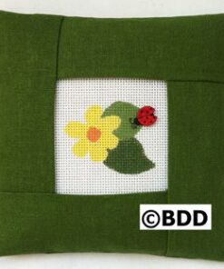 A green pillow with a picture of a flower and a ladybug.