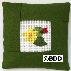 A green pillow with a picture of a flower and a ladybug.