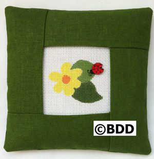 A green pillow with a picture of a flower and a ladybug.