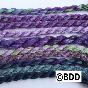 A group of purple and green yarn on top of each other.