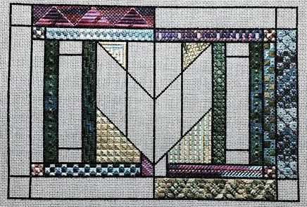 A cross stitch pattern of a quilt with the center panel in the middle.