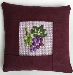 A pillow with grapes on it.