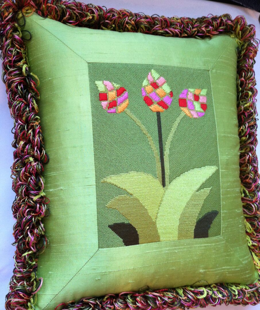 A green pillow with three flowers on it.