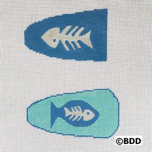 Two fish shaped needlepoint canvases with a blue background.