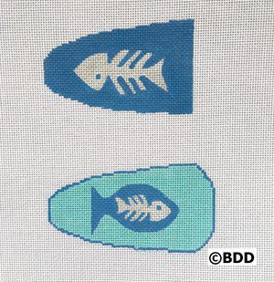 Two fish shaped needlepoint canvases with a blue background.