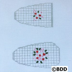 A pair of white slippers with red and green flowers.