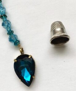 A necklace with a blue stone and a thimble