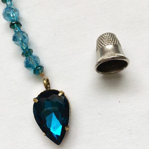 A necklace with a blue stone and a thimble