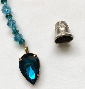 A necklace with a blue stone and a thimble