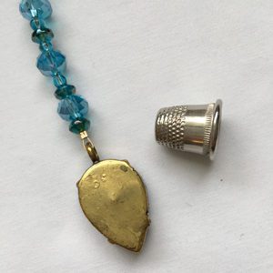 A necklace with a thimble and a leaf charm.