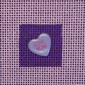 A heart shaped candy is on the purple background.