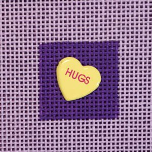 A heart shaped candy with the word hugs written on it.