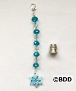 A blue bead with a small snowflake charm attached to it.