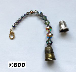 A bell is attached to the end of a beaded bracelet.