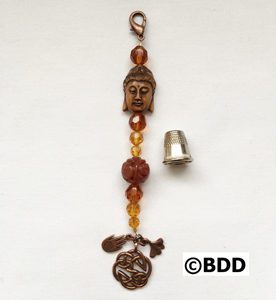 A metal bell with an ornament and beads.