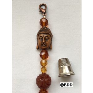 A thimble and bead with a buddha head