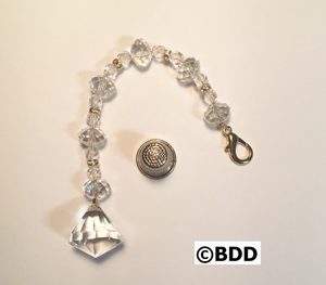 A small silver chain with a glass bead and a metal button.