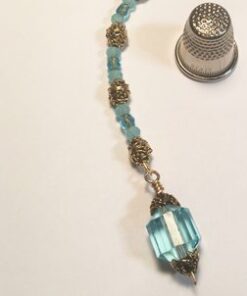 A blue bead necklace with a gold filigree pendant.