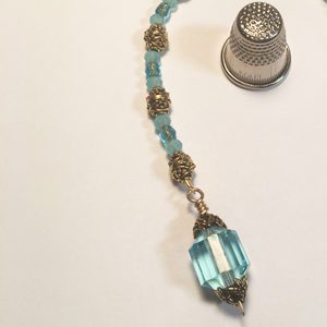 A blue bead necklace with a gold filigree pendant.