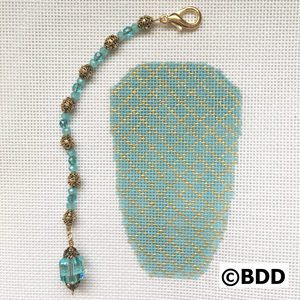 A blue bead is attached to the back of a piece of fabric.