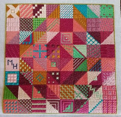 A cross stitch pattern of a quilt with many different colors.